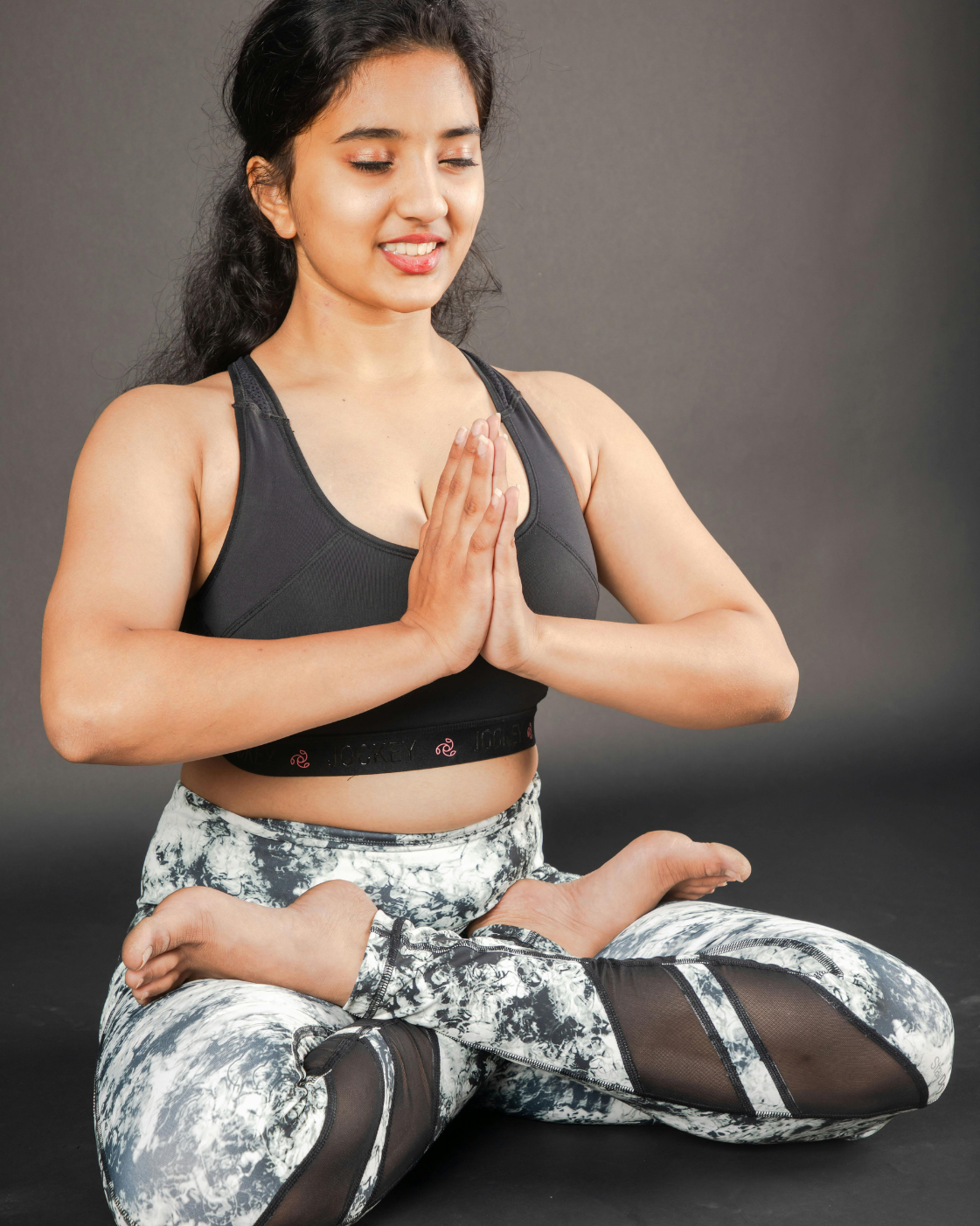 Woman sitting in lotus position with hands in prayer pose, practicing meditation for calmness and inner peace.
